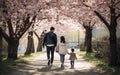 Back view of a mother, father and a baby walking at the park of cherry blossom. Generative AI Royalty Free Stock Photo