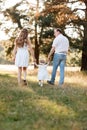 Back view of mother, father hold hands daughter enjoy nature and walk in the summer park. Young family spending time together on Royalty Free Stock Photo