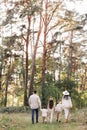 Back view of mother, father with three kids are walking, having fun in autumn forest. Family holding children hands Royalty Free Stock Photo