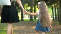 Back view of mother and her little daughter child walking together holding hands in summer park Royalty Free Stock Photo