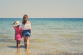 Back view mother and little daughter holding hands standing in sea water looking into horizon, copy space for text Royalty Free Stock Photo