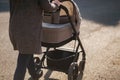 Back view of mother walking with her baby in stroller. Grey stroller outside, sunset Royalty Free Stock Photo