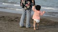 Back view of mother and young child with diaper walking at beach parenting and teaching concept