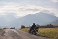 Biker in black leather outfit driving modern powerful motorcycle along sunny road on summer day. Royalty Free Stock Photo