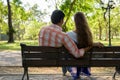 Back view of multi ethnic couple sitting on wooden bench in love Royalty Free Stock Photo