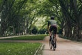 Back view of muscular cyclist in helmet biking at park