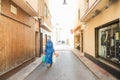 Back view muslim woman in blue modern clothes with some food bags walking on street with fasion shops. Everyday lifestyle. Copy Royalty Free Stock Photo