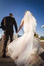 Back view of newlyweds walking along the road