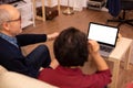 Back view of old couple in their living room looking a laptop with white isolated mock-up Royalty Free Stock Photo