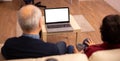 Back view of old couple in their living room looking a laptop with white isolated mock-up Royalty Free Stock Photo