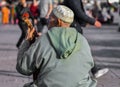 Back view of an old man with traditional dress and designer round cap sitting on road playing a musical instrument Sitar, Canada