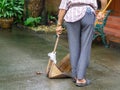 Back view of old man using broom sweep garbage at sidewalk