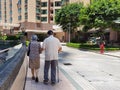 Back view of old spouses on a walk with stick in residential area, Hong Kong. Grandfather holding grandmother`s hand. Support and