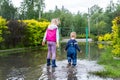 Back view of pair of two cute blond caucasian little children brother and sister enjoy have fun playing jumping in dirty Royalty Free Stock Photo