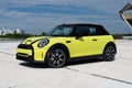 Back view of parked Mini Cooper in yellow color outdoors. Beautiful electrical automobile with rounded shapes and