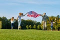 Back view, patriotic family moving with huge american flag.