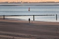 Back view of a person walking a dog along the sandy coastline in Norderney, Germany Royalty Free Stock Photo