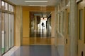 Back view of a person walking in the long empty hallway in a building