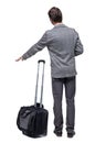 Back view of pointing business man with suitcase talking on the phone