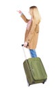 Back view of pointing woman with suitcase looking up. Royalty Free Stock Photo