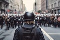 Back view of police officer with helmet and blurry crowd of protesting people in background