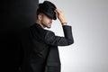 Polite young man holding black hat in studio