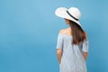 Back view portrait of elegant fashion young woman in white summer large wide brim sun hat, dress put hands on head Royalty Free Stock Photo