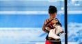 Back view portrait of little girl holding figure skates standing by ice rink and watching training, copy space Royalty Free Stock Photo