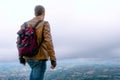 Back view Portrait of a man dressed in a stylish brown leather jacket and jeans. backpack watches and biker gloves. Travel conce[t