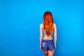 Back view portrait of sexual stylish girl with long ginger fair hair wearing in short jeans shorts and shirt. She has