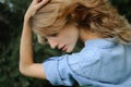 Back view portrait of sexy blonde girl with curly hair wearing blue casual jeans blouse posing in the park on green Royalty Free Stock Photo