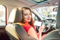 Back view Portrait of smiling caucasian young woman driver looking at camera and holding modern white digital tablet computer pc Royalty Free Stock Photo