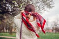 Back view of stylish woman wearing red hair scarf in spring park. Retro female fashion. Headscarf for bun hairstyle Royalty Free Stock Photo