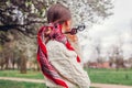 Back view of stylish woman wearing red hair scarf in spring park. Retro female fashion. Headscarf for bun hairstyle Royalty Free Stock Photo