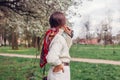 Stylish woman wearing red hair scarf white sweater pants in spring park. Female fashion. Headscarf hairstyle Royalty Free Stock Photo