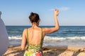 Back view portrait young adult woman holding cold alcohol refresh beverage glass looking at ocean shore at summer Royalty Free Stock Photo