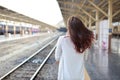 Back view portrait of young asian woman in white dress with sun glassess standing while waiting in train station