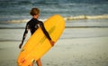 Back view portrait of young happy surfer girl walking towards the sea carrying yellow surf board and ready for surfing enjoying su Royalty Free Stock Photo