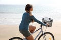 Back view portrait of young woman riding on bicycle enjoying sun on the beach Royalty Free Stock Photo