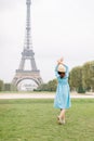 Back view of pretty lady in blue dress and hat, enjoying walk in Paris, near Eiffel tower. Young attractive happy woman Royalty Free Stock Photo