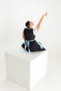 Back view of pretty woman, waitress in traditional Austrian or Bavarian costume sitting on huge box isolated over white Royalty Free Stock Photo