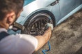 Service station worker power-washing the car wheel