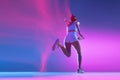 Back view. Professional female athlete running away isolated on blue studio background in mixed pink neon light. Healthy Royalty Free Stock Photo