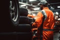 Back view of professional mechanic and new car tyre stack at auto repair shop. Technician man at auto repair service center. Royalty Free Stock Photo