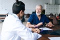 Back view of professional team senior adult and young doctors discussing and working together sitting at desk in medical Royalty Free Stock Photo