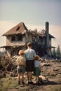 back view of refugee family looking at destroyed home after war, desperate people near demolished house after natural Royalty Free Stock Photo