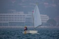 Back view of a sailor in a sailboat on a competition in Optimist class on open waters on the sea during sunny weather