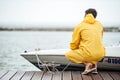 Back view of a sailor in yellow cloak at pier