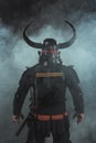 back view of samurai in traditional armor and horned helmet on dark background Royalty Free Stock Photo