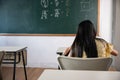 Back view of school girl on lesson in classroom write hardworking on blackboard Royalty Free Stock Photo